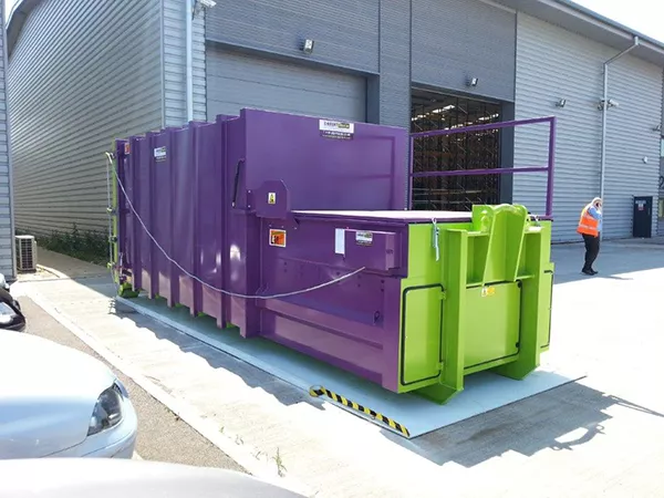 The purple Model L Roro compactor outside a warehouse.