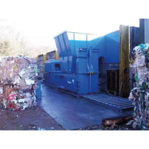 The CB65Wt baler in an outside environment surrounded by baled materials.